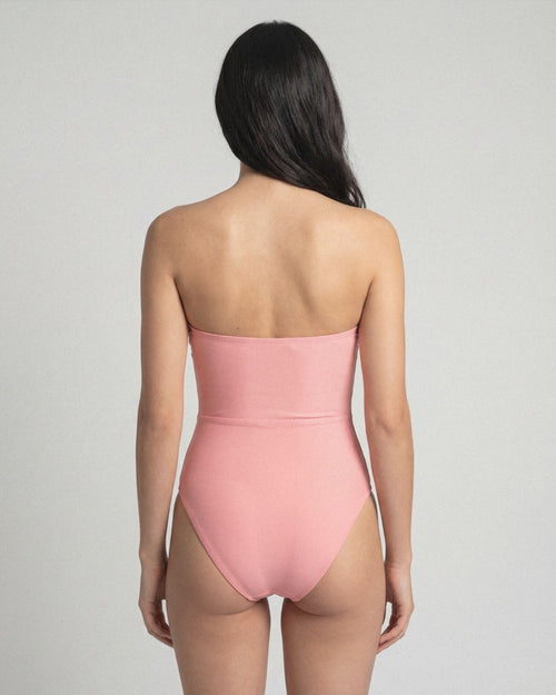 Person wearing a pink strapless swimsuit against a gray background