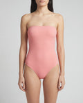 Woman wearing a pink strapless swimsuit against a plain background