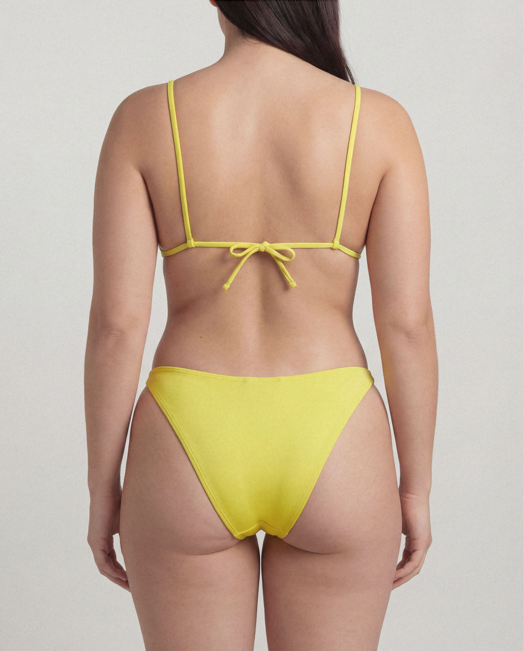 Yellow bikini with thin straps on a plain background