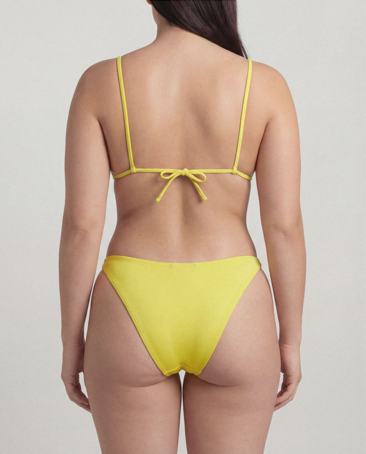 Yellow bikini with thin straps on a plain background