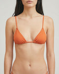 Woman wearing an orange bikini against a plain background