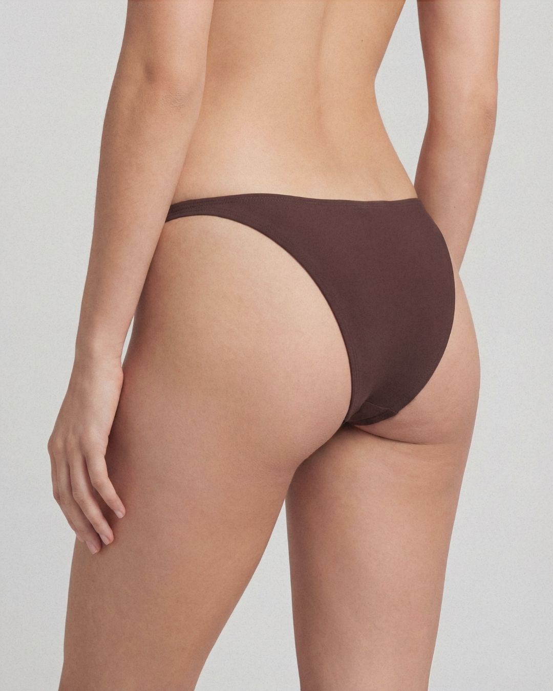 Brown bikini bottom worn by a person on a plain background