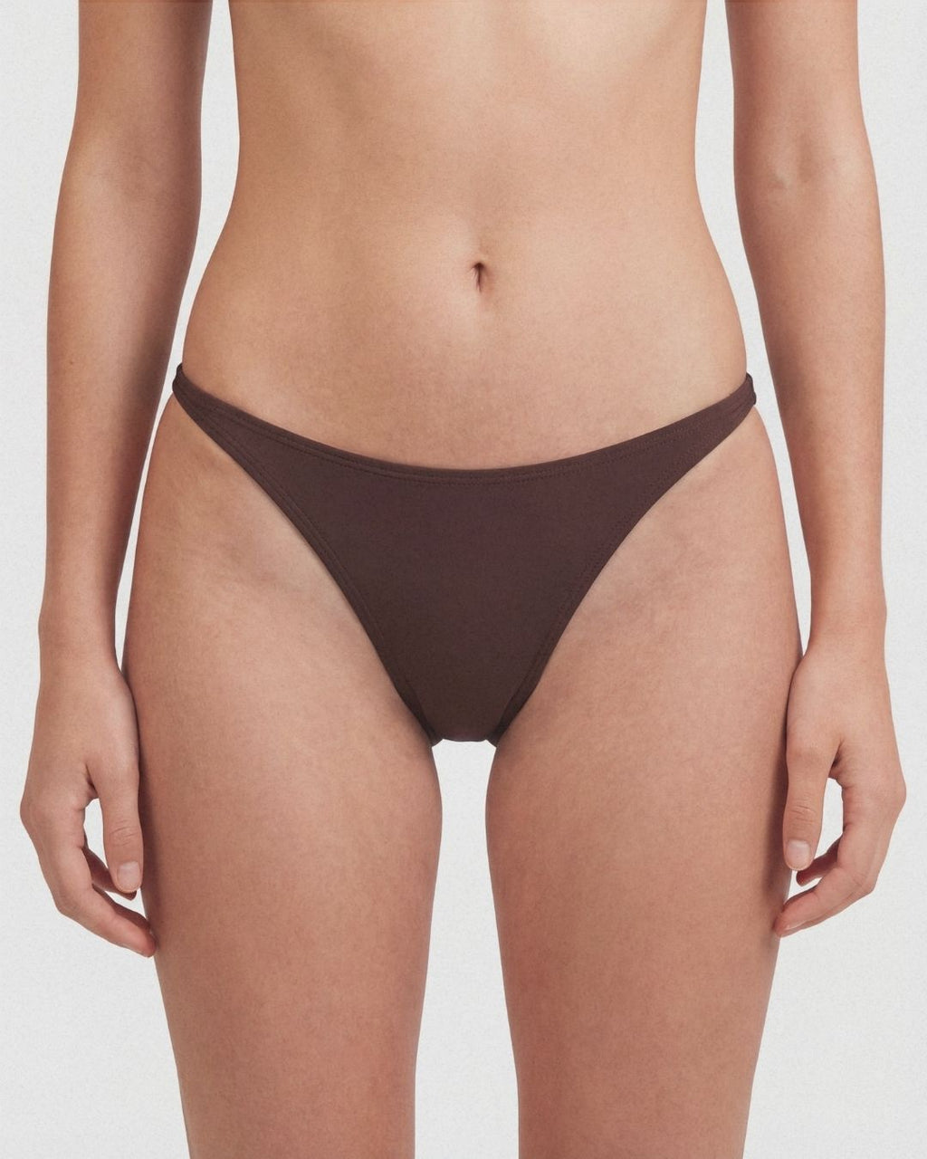Brown bikini bottom worn by a person on a white background