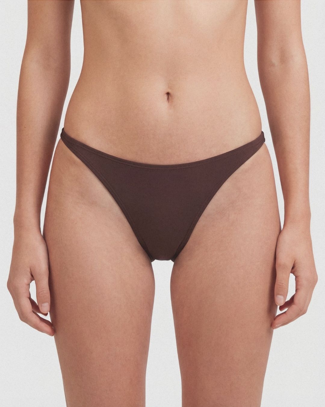 Brown bikini bottom worn by a person on a white background
