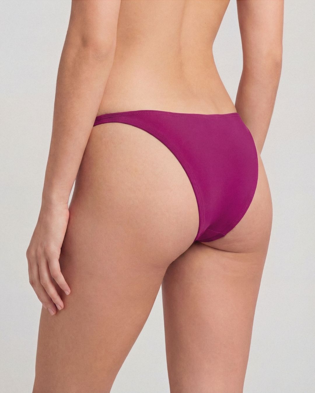 Purple bikini bottom worn by a person on a plain background