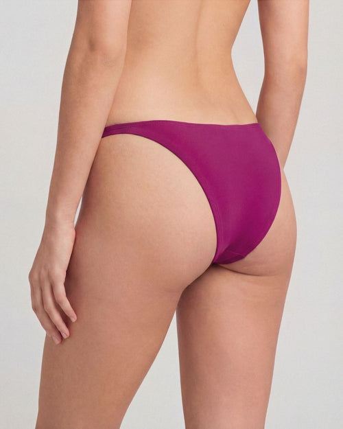 Purple bikini bottom worn by a person on a plain background