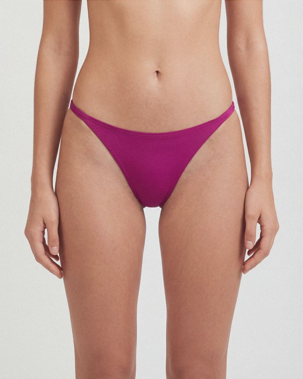 Purple bikini bottom worn by a person on a white background