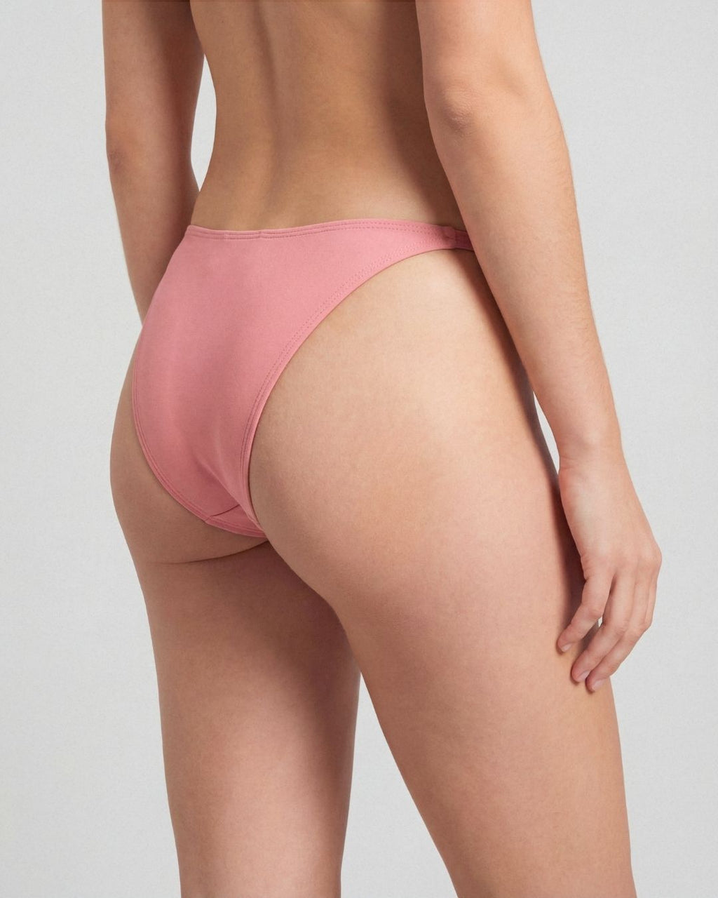 Person wearing a pink bikini bottom on a plain background