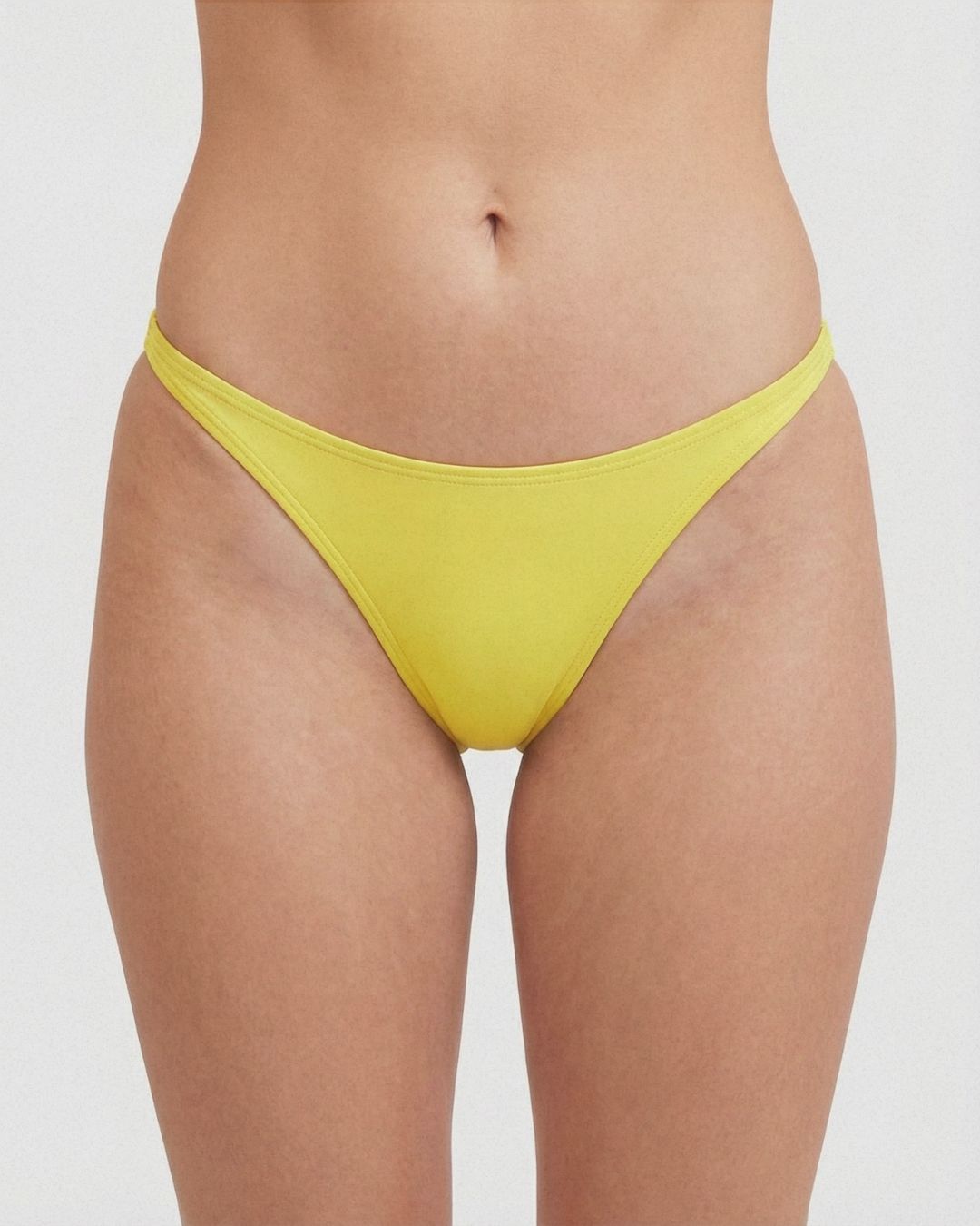 Yellow bikini bottom worn by a person on a white background