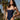 Woman wearing a navy blue swimsuit with palm trees in the background