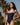 Woman wearing a navy blue swimsuit with palm trees in the background