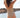 Woman in a beige swimsuit standing by a body of water with a scenic background