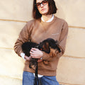 Girl wearing masara cacao sweatshirt and holding small dog 