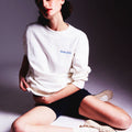 Girl sitting down posing and wearing masara cream sweatshirt