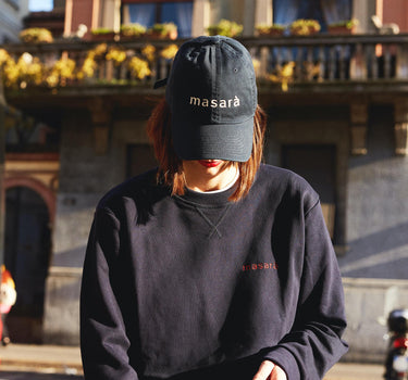 Girl on the street looking inside her bag and wearing masara navy blue dad hat and sweatshirt