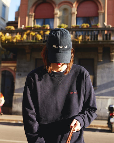 Girl on the street looking inside her bag and wearing masara navy blue dad hat and sweatshirt