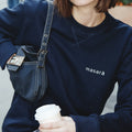 Girl on the street holding her coffee wearing masara navy blue and cream logo sweatshirt