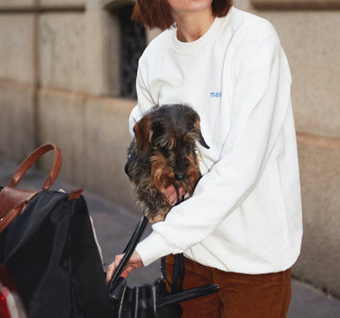 Girl holding a small dog wearing masara pink dad hat and the cream sweatshirt crewnewck