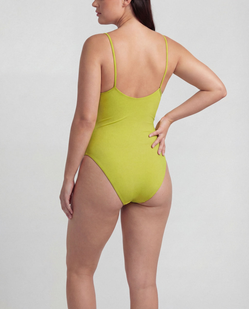 Woman wearing a lime green swimsuit on a light gray background