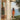 Woman in an orange swimsuit walking towards a scenic view of the ocean from a modern outdoor setting.