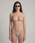 Woman wearing a beige bikini against a plain background