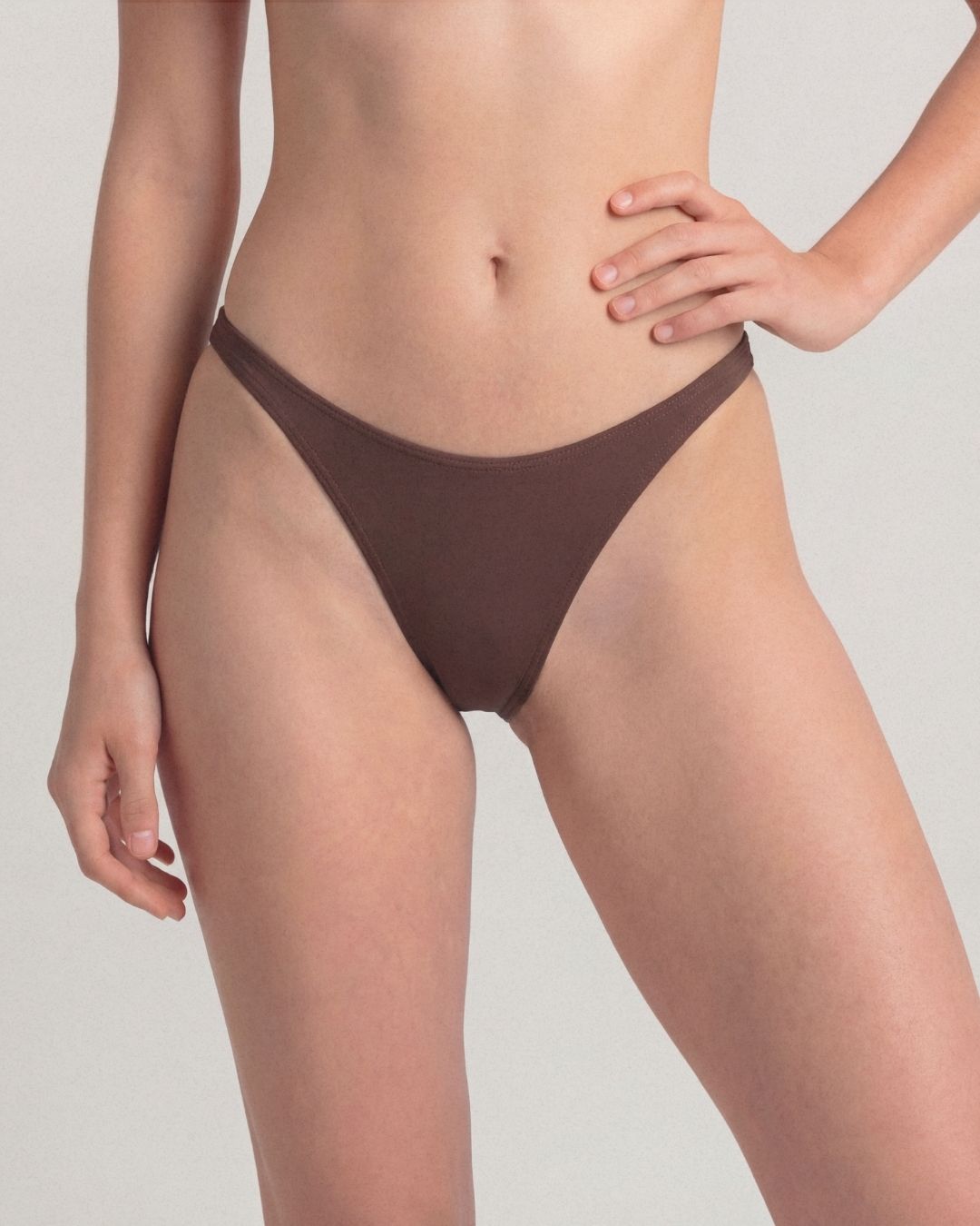 Brown bikini bottom worn by a person on a light gray background