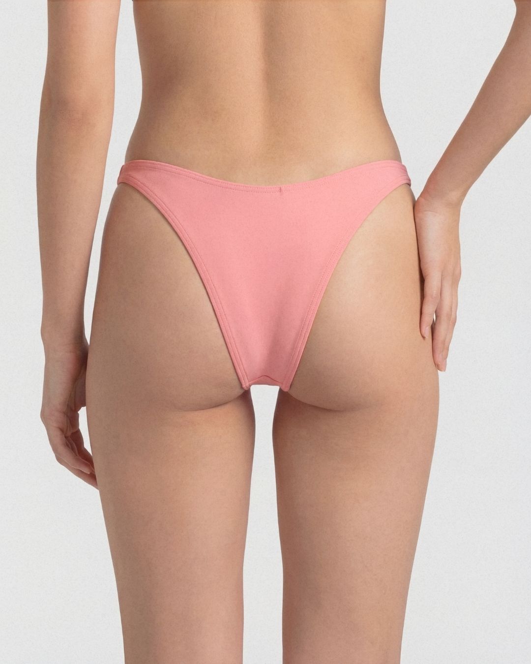 Pink bikini bottom worn by a person on a white background