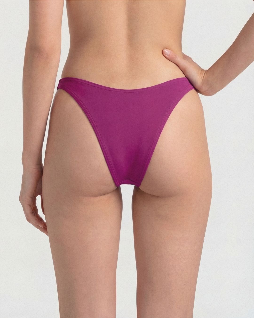 Purple bikini bottom worn by a person on a plain background