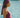 Woman in a pink swimsuit and headscarf by a body of water