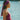 Woman in a pink swimsuit and headscarf by a body of water