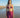 Woman in a purple bikini and sarong standing on a beach.