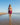 Woman in a purple bikini standing on a beach with clear blue sky