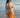 Woman in an orange bikini standing on a beach with ocean in the background