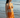 Woman in an orange bikini standing on a beach with ocean waves in the background