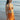 Woman in an orange bikini standing on a beach with ocean in the background
