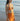 Woman in an orange bikini standing on a beach with ocean in the background