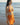 Woman in an orange bikini standing on a beach with ocean in the background