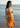 Woman in an orange bikini standing on a beach with ocean waves in the background