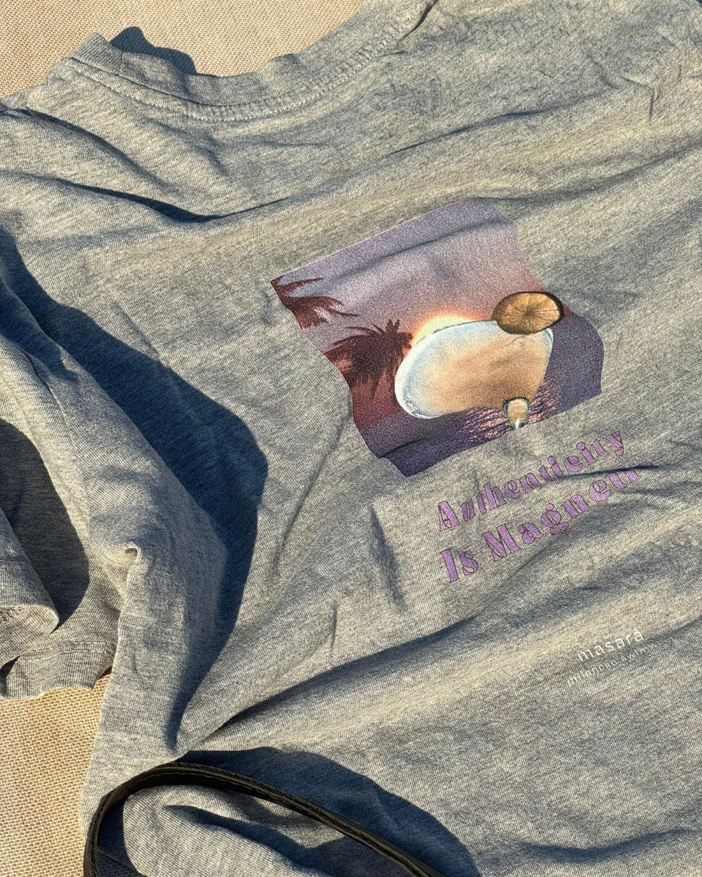 Model wearing the Magnetic Tee in Heather Grey, with the authenticity is magnetic artwork printed on the back