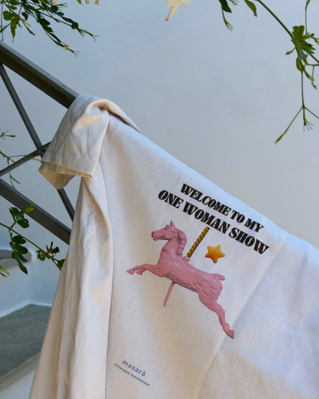 Model wearing the One Woman Show Tee in Off-White, with the welcome to my one woman show artwork printed on the back