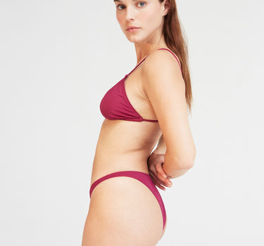 Model showcasing the Coco Bikini Bottom in Grape Purple, featuring classic briefs and medium coverage made from regenerated nylon.