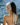 Woman with a beige headscarf sitting by a body of water