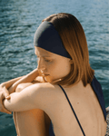 Woman wearing a dark blue swim cap and bikini top by the water