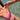 A close-up lifestyle shot of a person wearing a dusty pink one-piece swimsuit, standing in clear, shallow turquoise water.