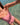 A close-up lifestyle shot of a person wearing a dusty pink one-piece swimsuit, standing in clear, shallow turquoise water.