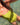A woman wearing a bright lime green one-piece swimsuit, photographed from above while floating in clear, sunlit shallow water.