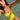A woman in a bright yellow one-piece swimsuit taking a selfie in clear, shallow turquoise water.