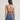 Woman wearing a brown halter top and blue jeans on a plain background