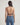 Woman wearing a brown halter top and blue jeans on a plain background