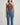 Person wearing a brown halter top and blue jeans on a light gray background